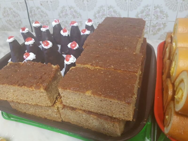Fatias de bolo de canela empilhadas num tabuleiro, ao lado de pirâmides de chocolate com uma cereja.