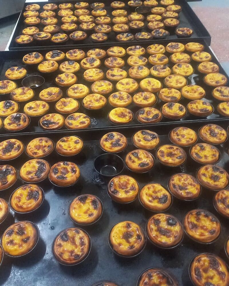 Tabuleiros de pastéis de nata acabados de sair do forno, em cima das bancadas da fábrica.